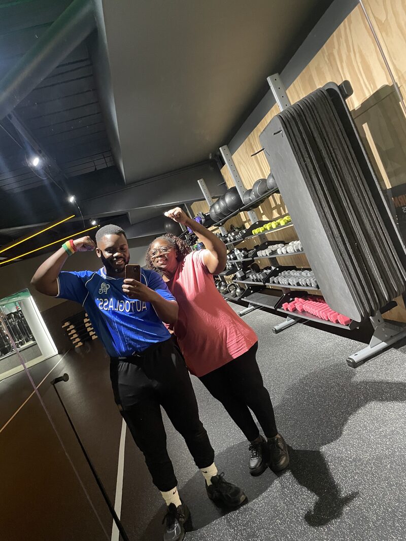 Kenny and a client flexing in the gym